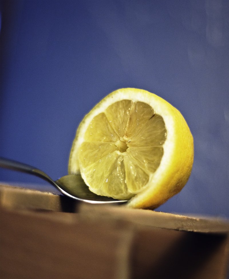 fresh ripe whole lemons in eco string bag on yellow background